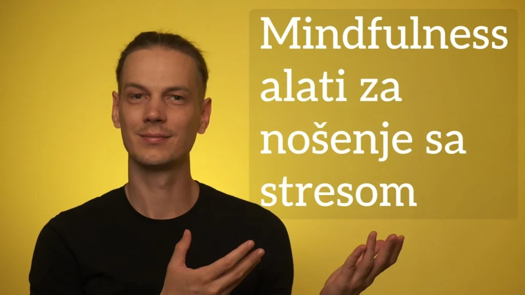Luka Šolta u crnoj majici ispred zlatne pozadine pokazuje na natpis "Mindfulness alati za nošenje sa stresom"